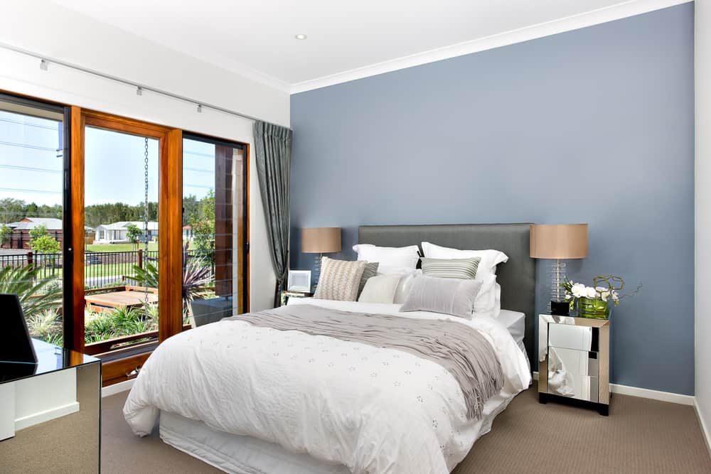 Modern decorative bedroom included king size bed with white sheets over it.